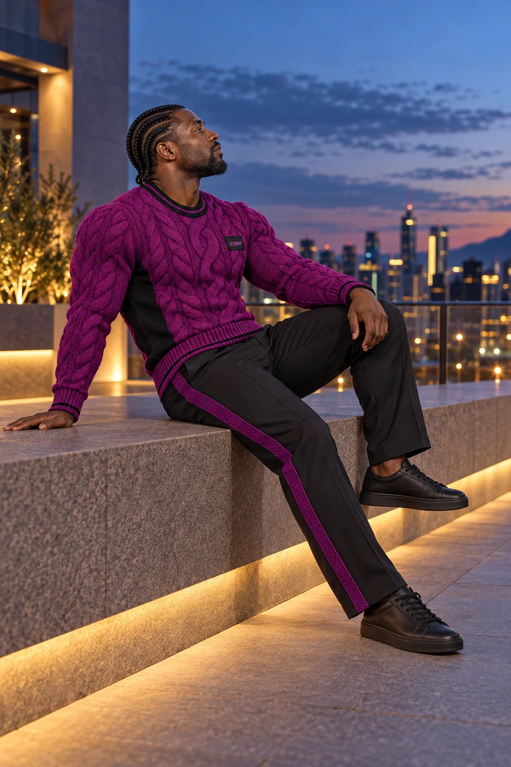 Cebisa seated in profile on a city terrace wearing the Jacaranda cable-knit sweater and tailored trousers